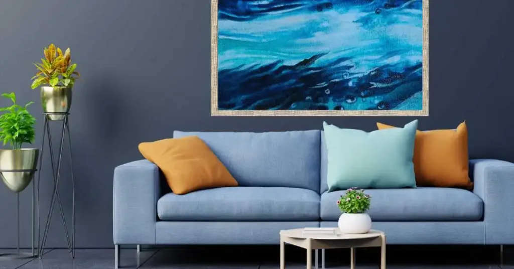 Livingroom with a blue sofa against a bluish-grey wall and abstract wall art for Coastal Vibes.