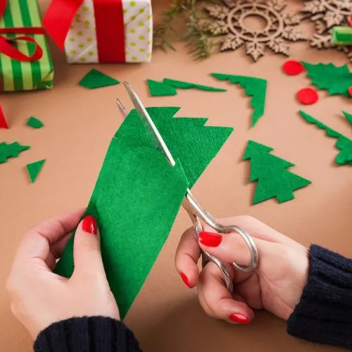 Close-up of hands engaged in paper cutting for DIY Christmas ornaments. Creative and Budget Friendly Christmas Decor Ideas in action. 