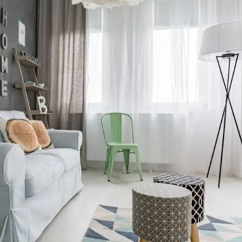 Softly illuminated living room in apartment adorned with fresh white sheer curtains.