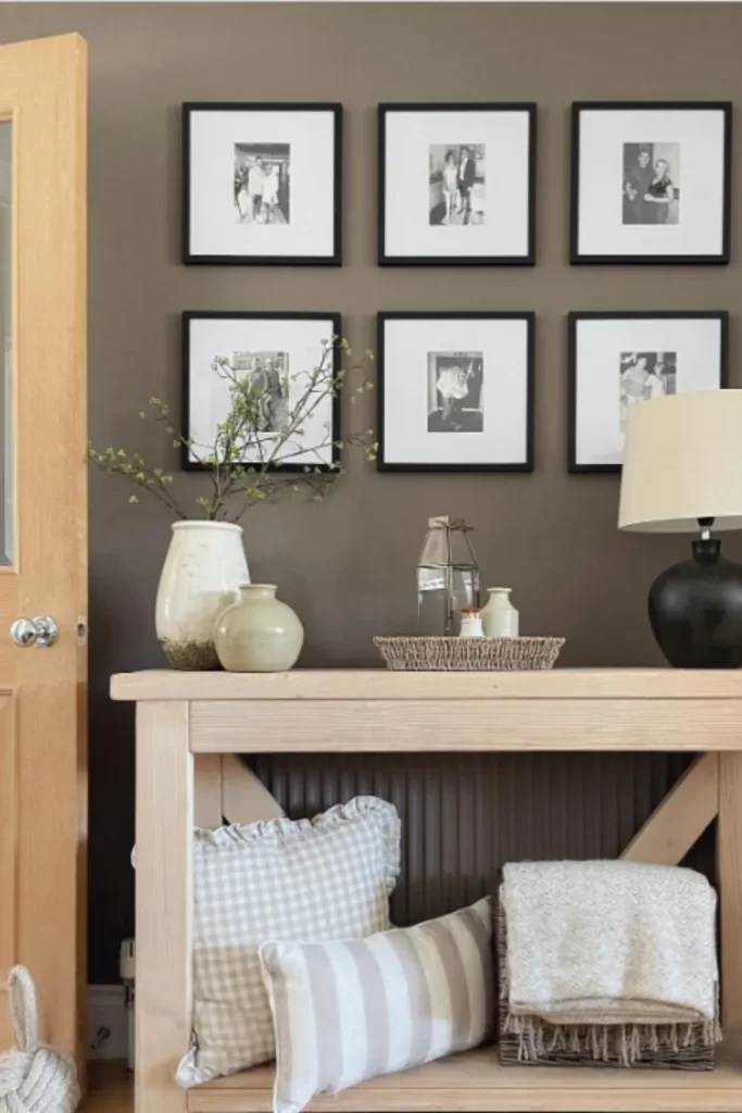 A natural wood console table decor with an X-frame design, decorated with ceramic vases and a tray of essentials on top