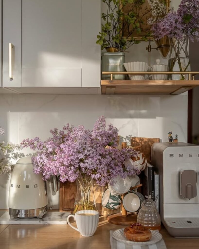 Budget friendly decor idea—a charming coffee bar created on a kitchen counter with delicate crockery and fresh flower bunches.