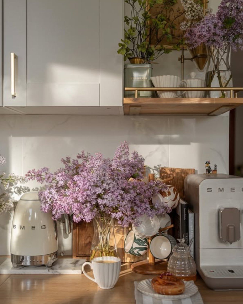Budget friendly decor idea—a charming coffee bar created on a kitchen counter with delicate crockery and fresh flower bunches.