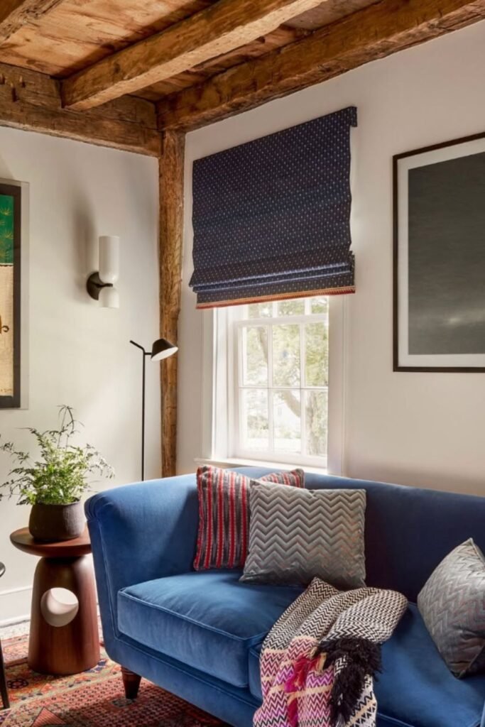 Blue velvet sofa with rustic wooden beams and cozy textiles