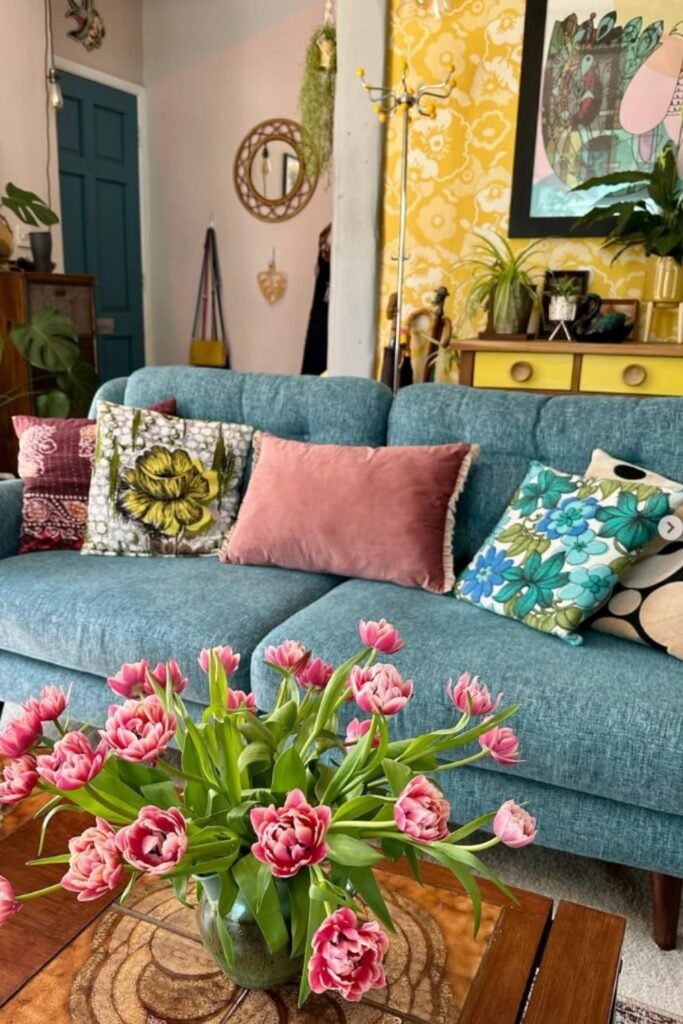 Blue sofa styled with floral and velvet cushions in a colorful living room