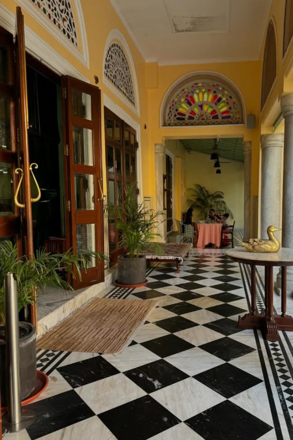 Traditional Indian veranda with checkered marble flooring and stained glass arches.