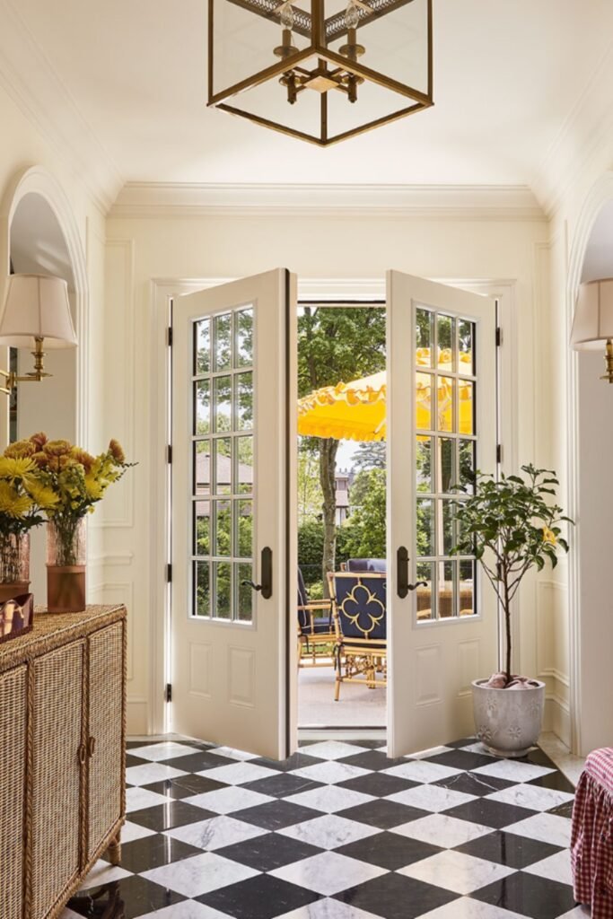 Beautiful Entryway with black and white checkered floor, wicker sideboard, and glass doors opening to a garden.