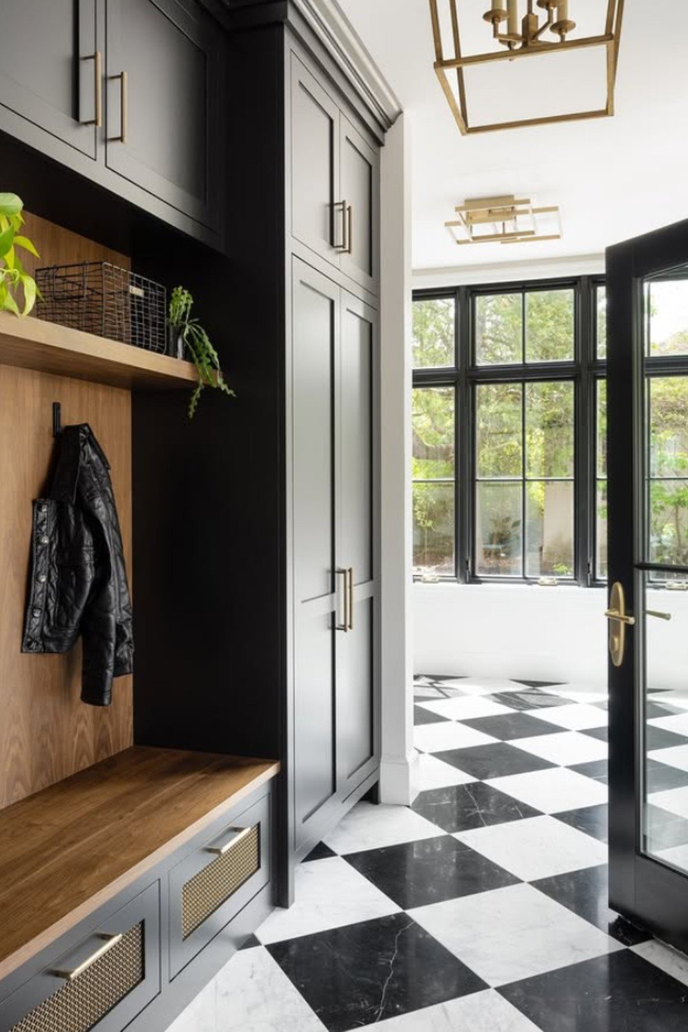Mudroom with white and black checkered floor, black cabinets, and wood bench.