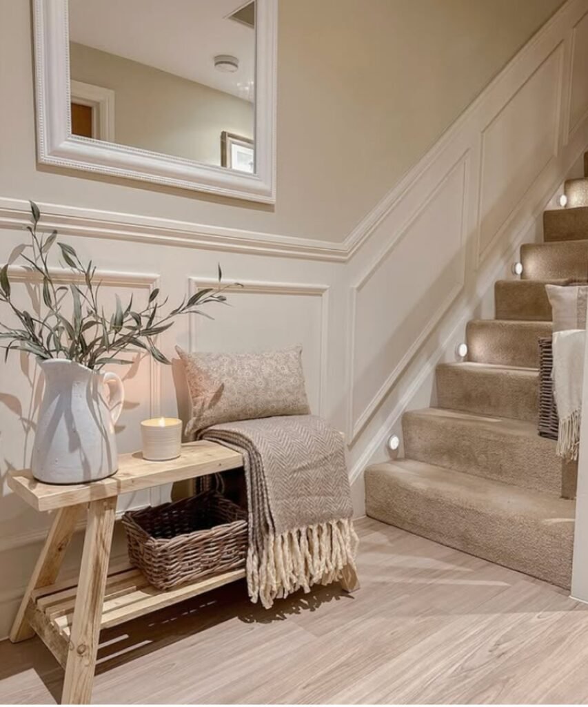 White pitcher with olive stems on entry bench with neutral décor.