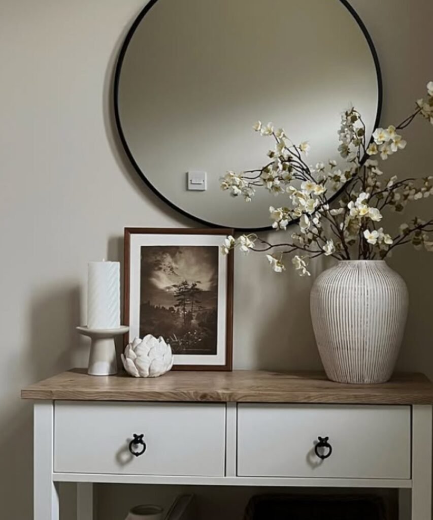 Minimalist ceramic vase with white blossoms in entryway setup.