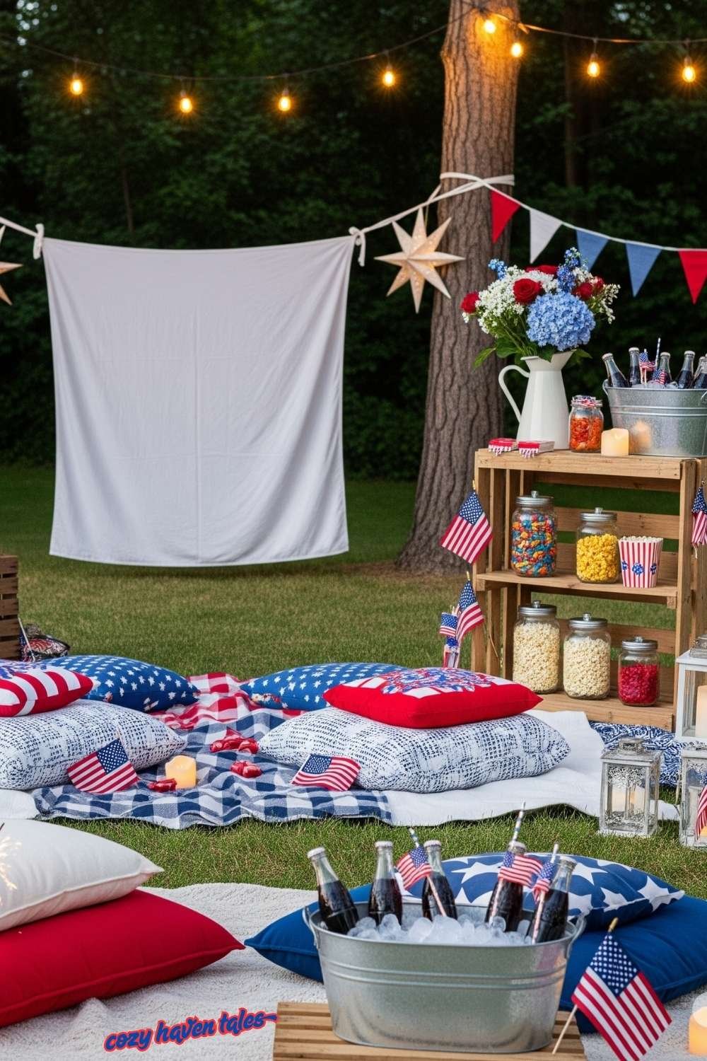 Outdoor movie setup with string lights, cushions, and white sheet projector screen.