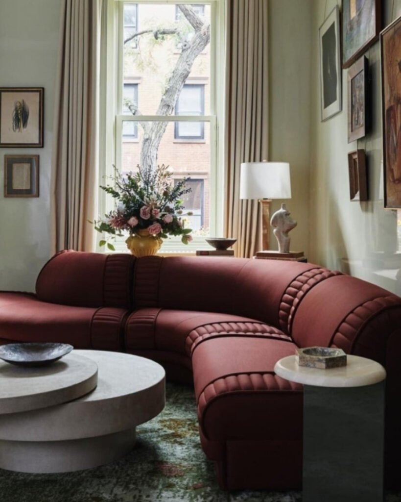 Curved burgundy sofa in a modern living room styled with cream accents and featuring a unique sofa color
