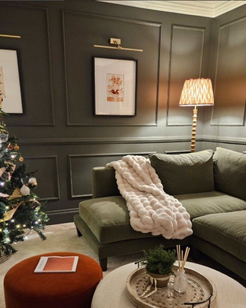 Olive green sectional sofa in a moody dark-paneled room with Christmas decor and a unique sofa color