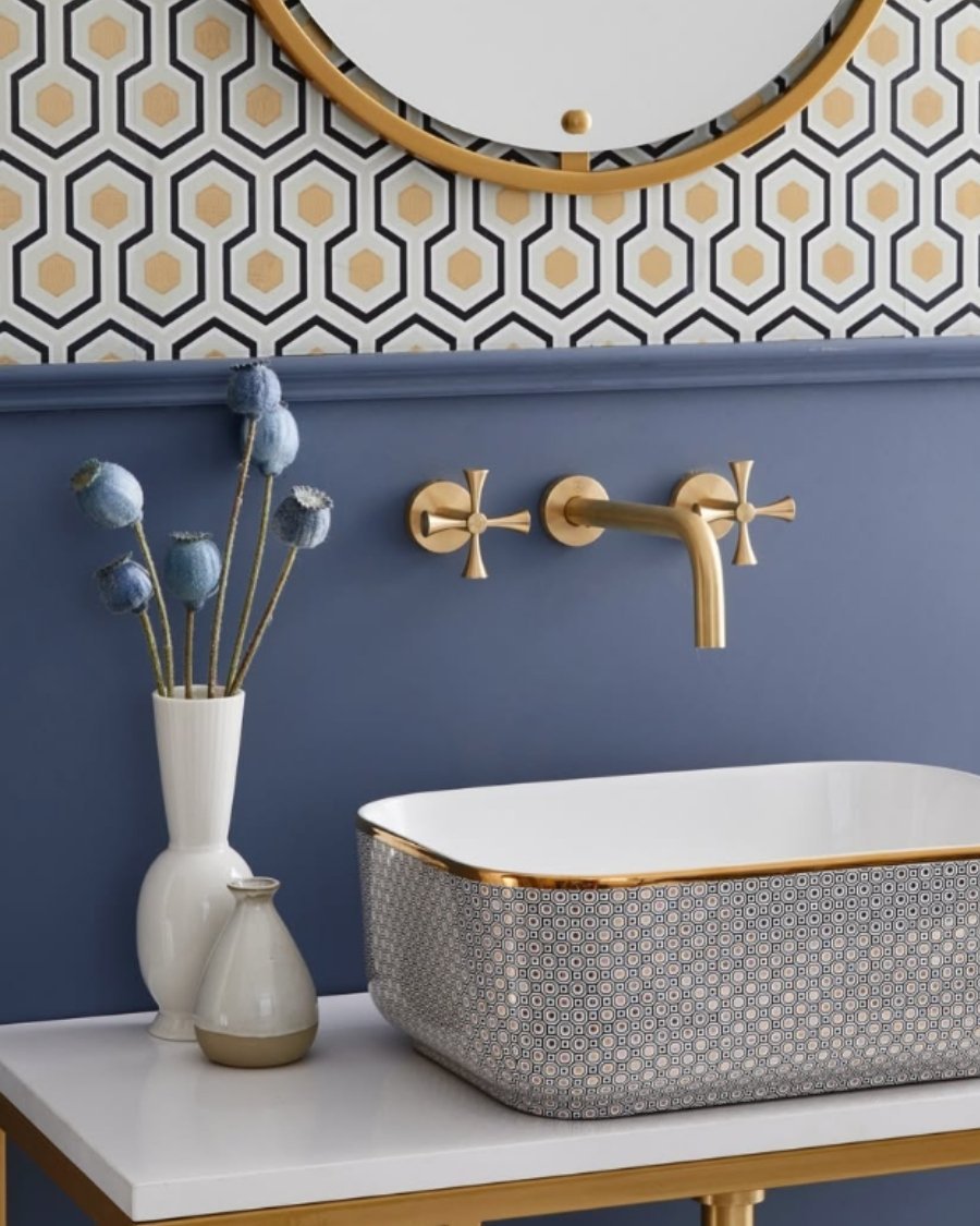 blue bathroom wall with hexagon tile backsplash, gold faucet, patterned sink