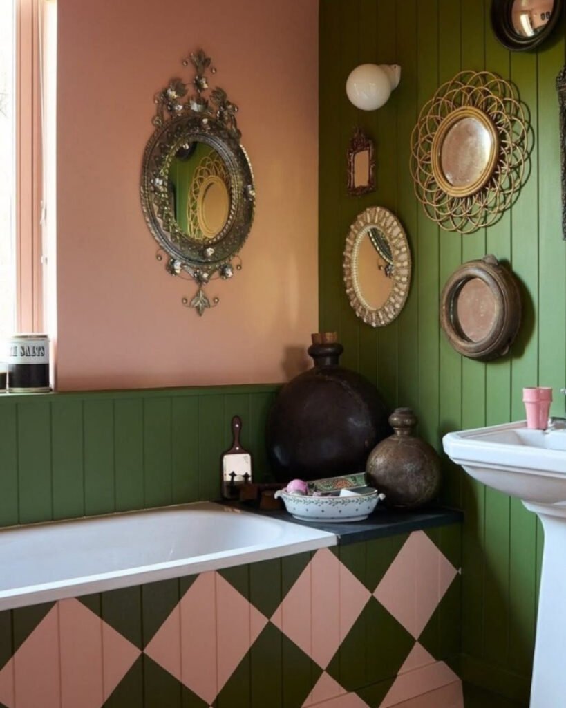 pink and green bathroom with diamond‑patterned tub panel and antique mirrors
