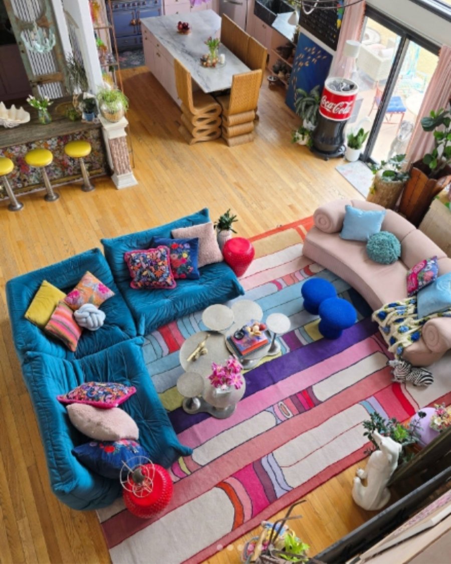 Colorful eclectic living room with blue modular sofa, striped rug, bubble coffee table, and bold pillows.