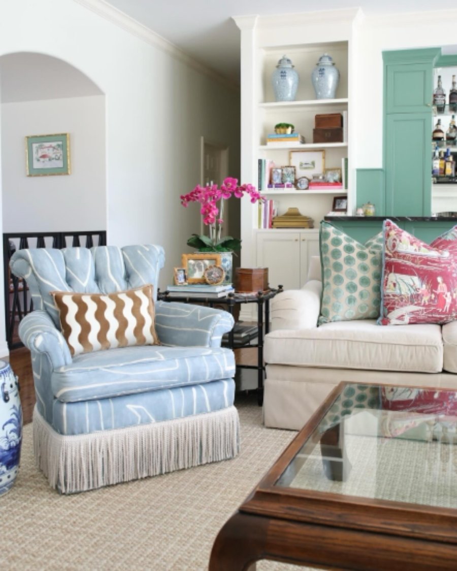 Soft decor with pale blue chair, neutral sofa, pink and green cushions, and mint cabinetry.