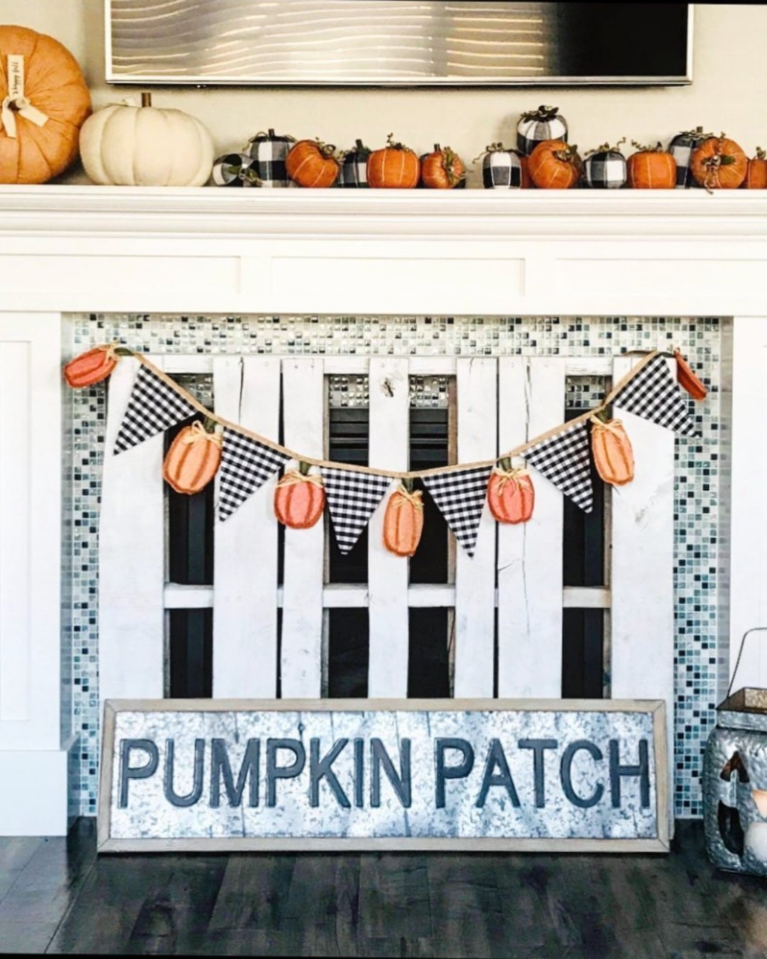 Fall mantel decorating ideas with a pumpkin patch sign, gingham bunting, and stacked mini pumpkins.