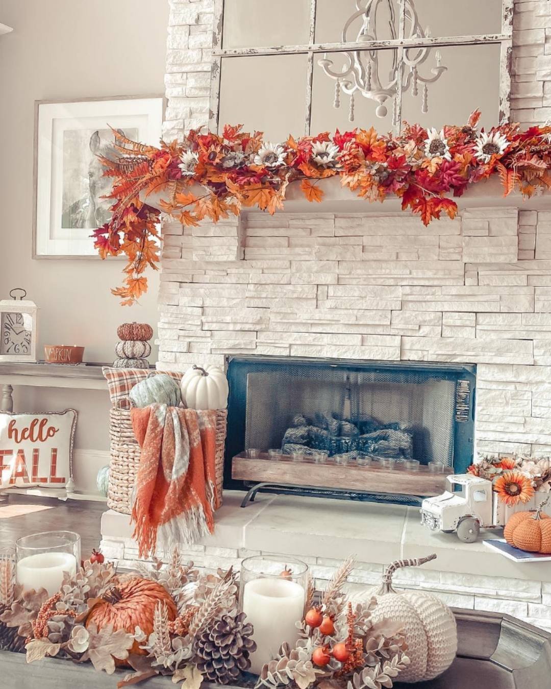 Bright fall mantel decorating ideas with white stone, soft pumpkins, and vibrant autumn leaf garlands.