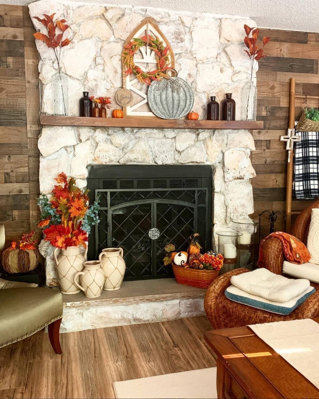Rustic fall mantel decorating ideas with stone, wood walls, pumpkin wreath, and cozy seasonal florals.