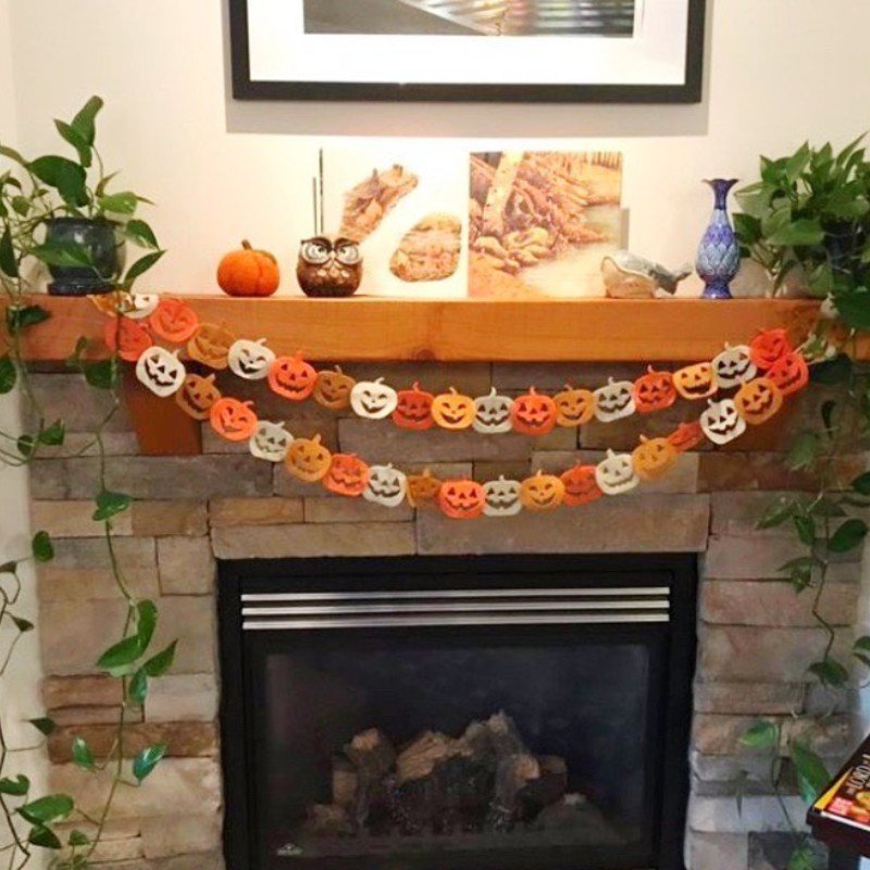 Playful fall mantel decorating ideas with jack-o'-lantern garland, mini pumpkins, and simple greenery.