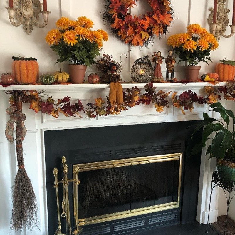 Fall mantel decorating ideas with orange leaf garlands, yellow fall florals, and a pumpkin wreath centerpiece.