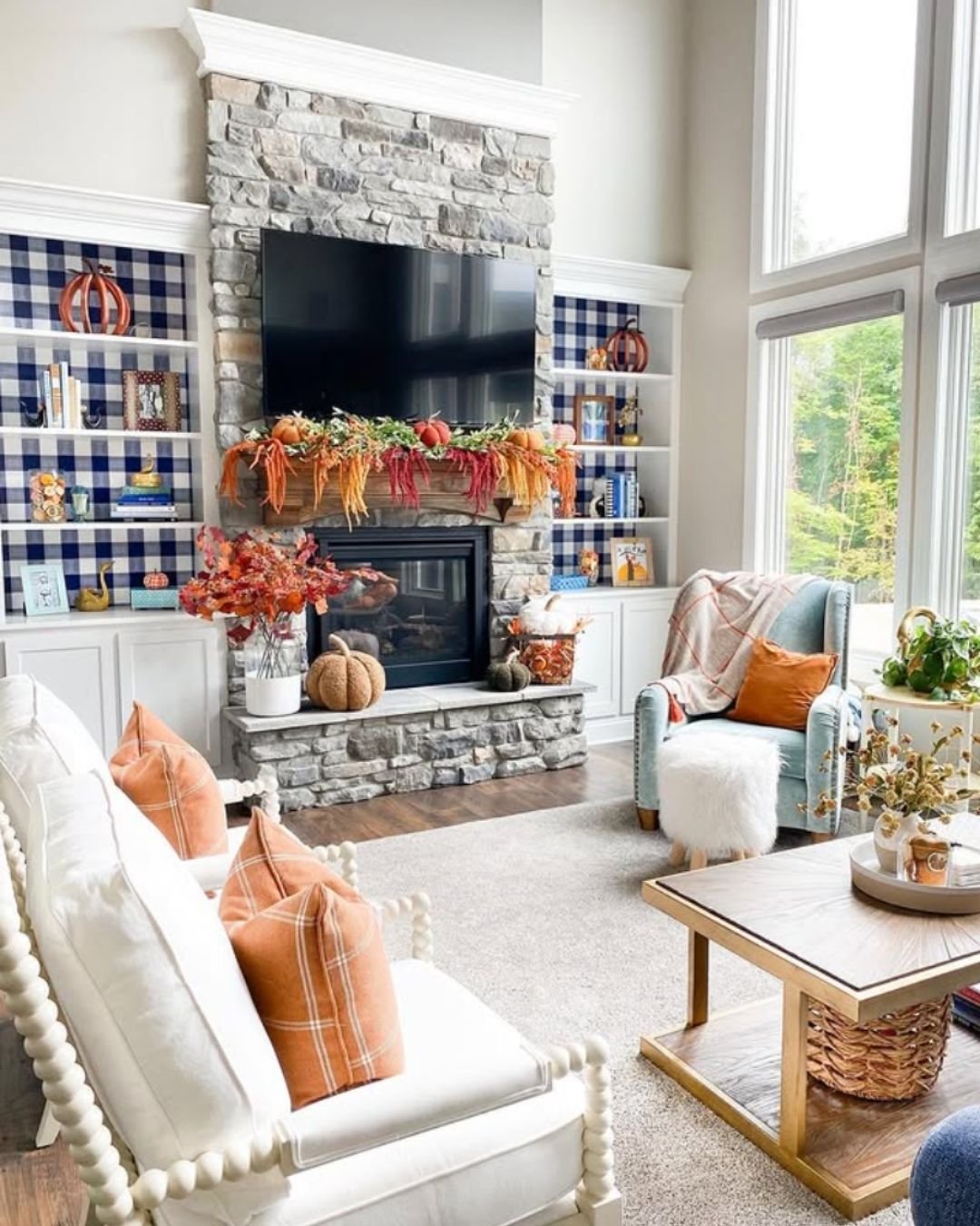 Classic fall mantel decorating ideas with soft autumn garland, cozy plaid shelf accents, and warm neutral tones around a stone fireplace.