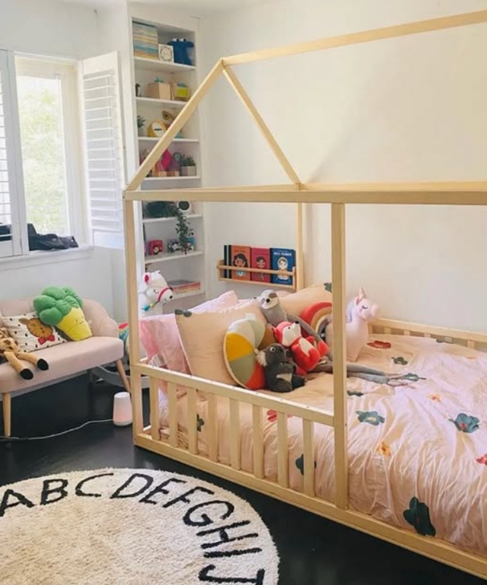 Montessori floor bed with pastel sheets and colorful stuffed toys