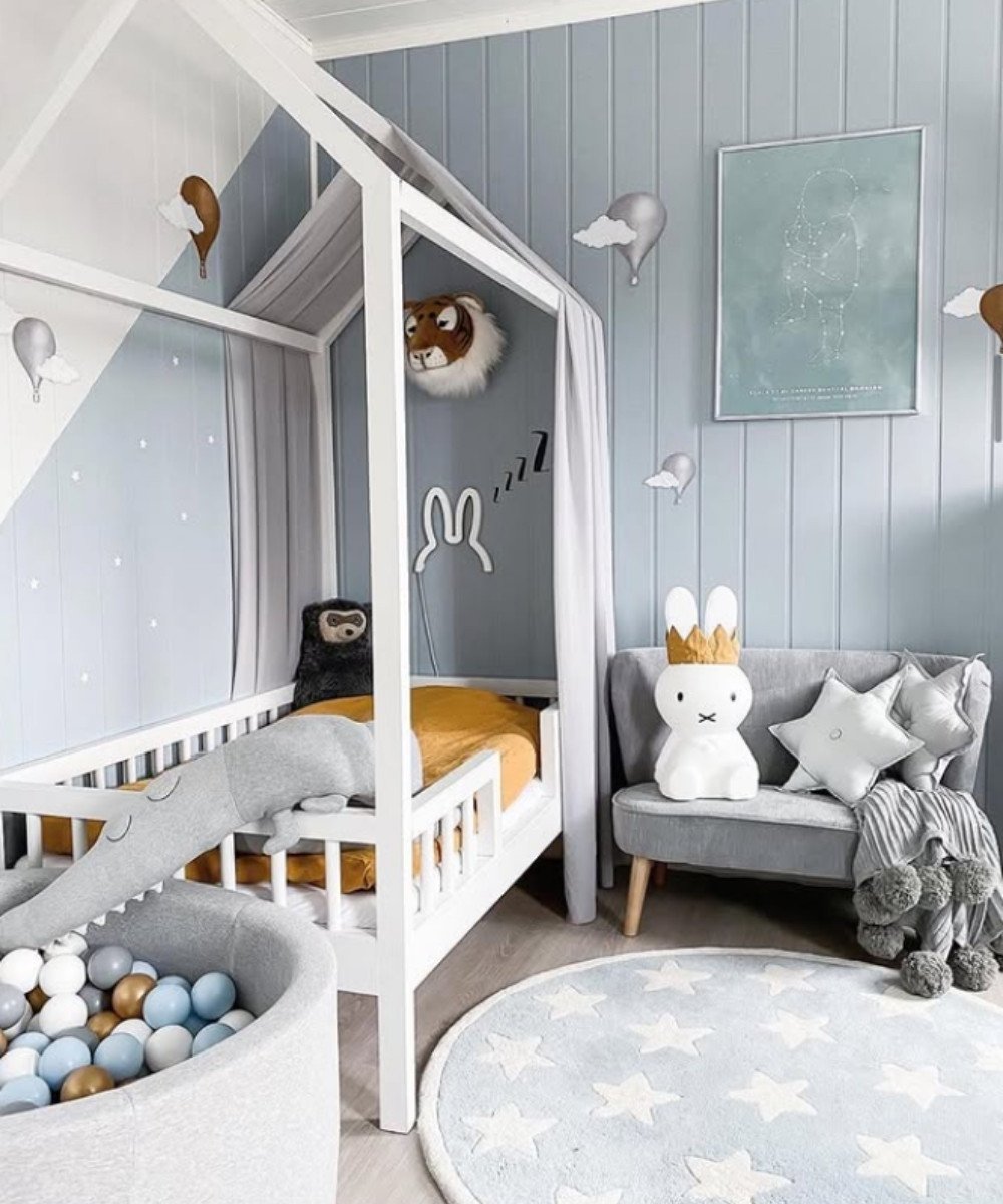 Montessori room with blue walls, white house bed, and star rug