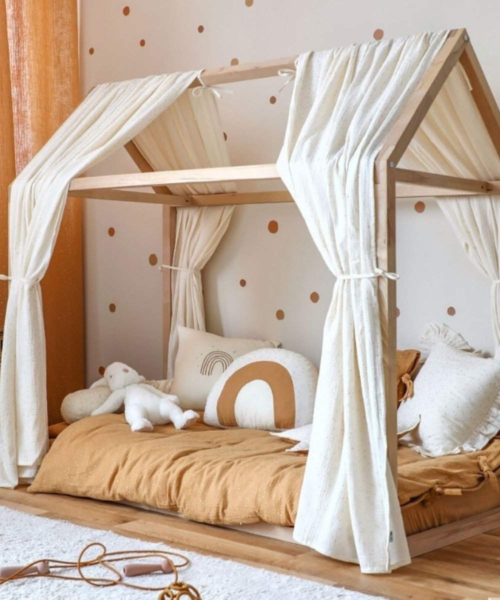 Montessori room with ochre bedding, house bed, and polka dot wallpaper