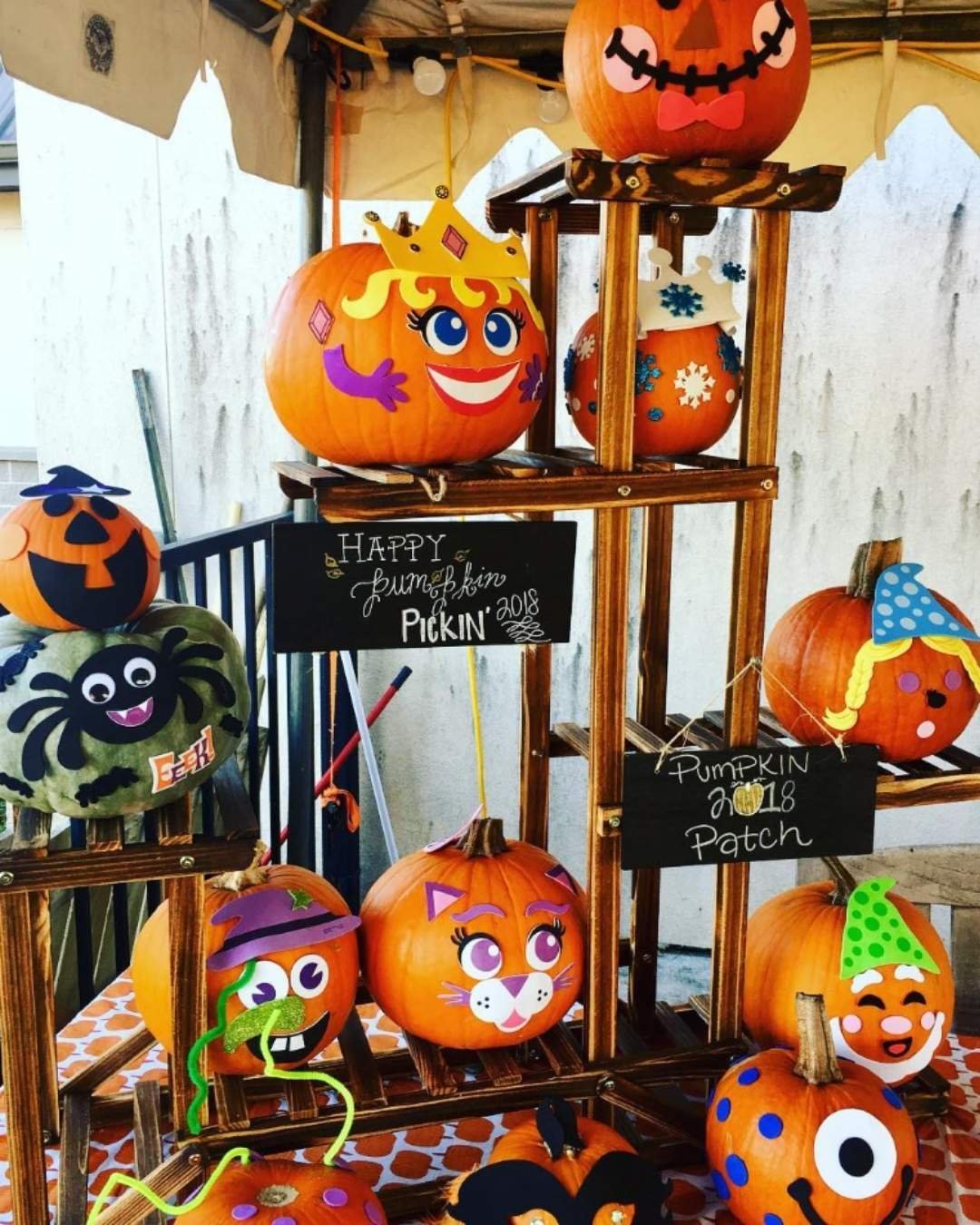Multiple Pumpkin Decorating Ideas with colorful cartoonish faces arranged on wooden stands with fun signs.