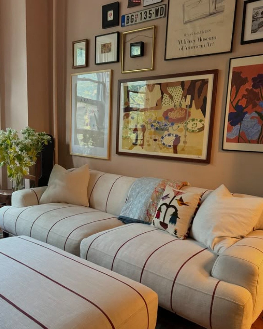 Cream-colored striped sofa with red lines in a cozy living room with gallery wall