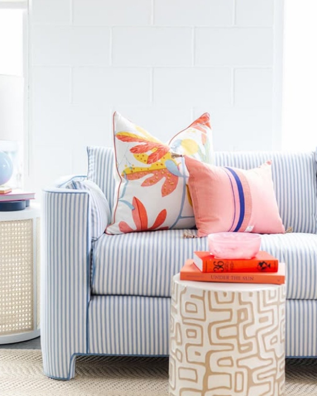 Light blue striped sofa with pastel and floral pillows in a bright room