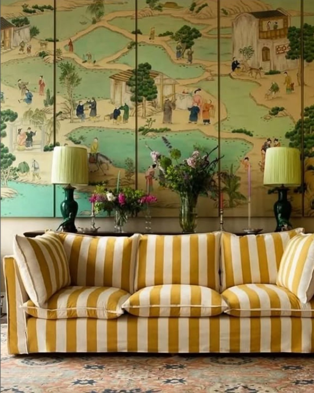 Mustard yellow striped sofa in front of traditional chinoiserie mural