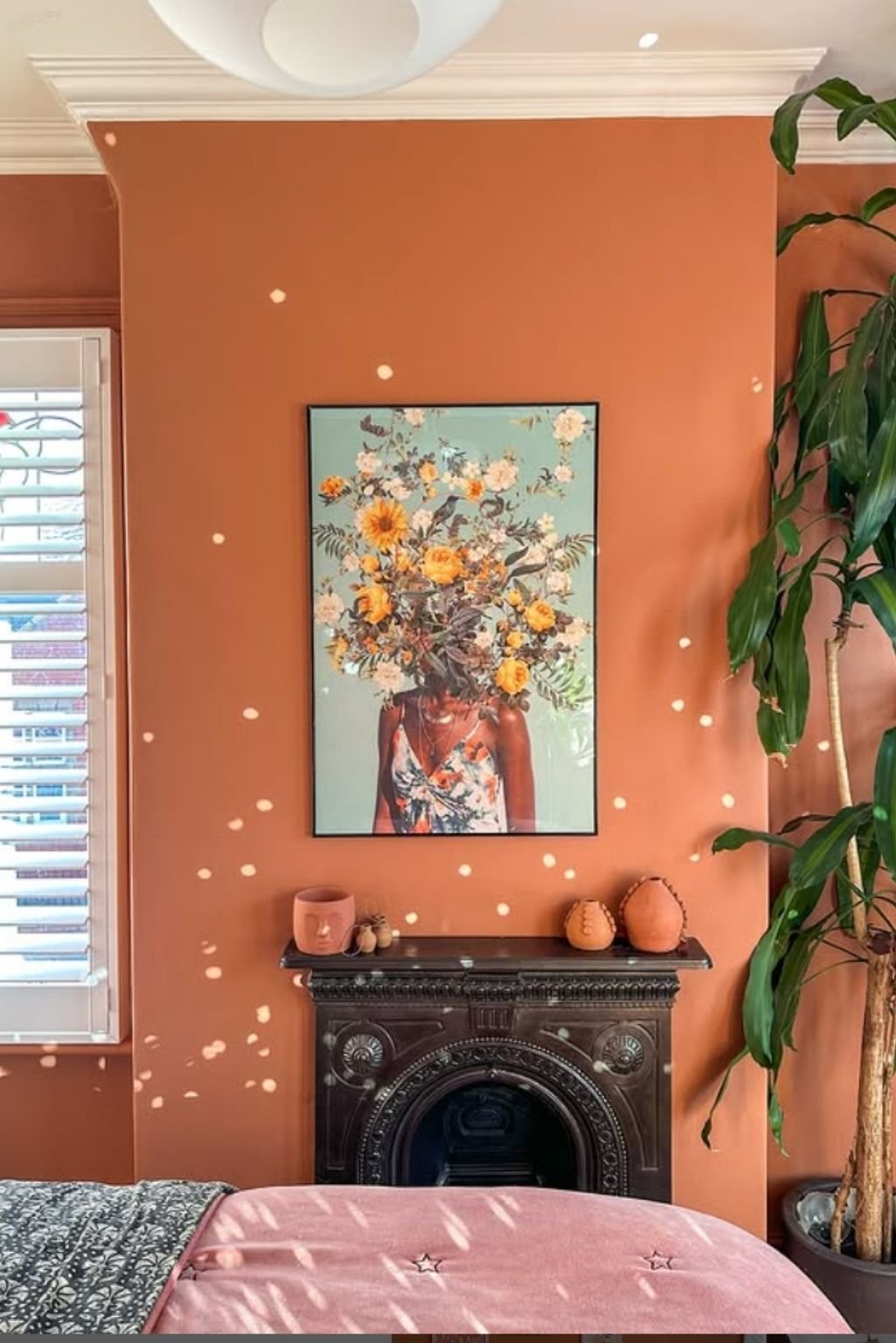 Warm and cozy space with burnt orange walls, floral art, and minimal styling—an inviting example of orange color bedroom ideas.