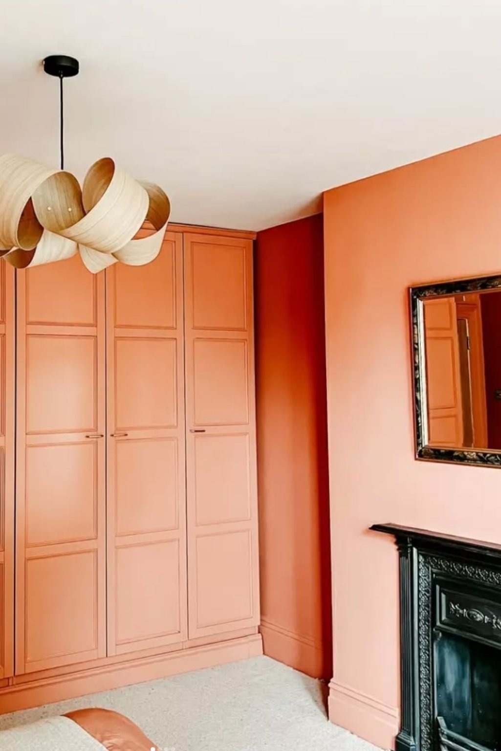 Built-in wardrobe and matching orange wall paint for cohesive orange color bedroom ideas in modern homes.