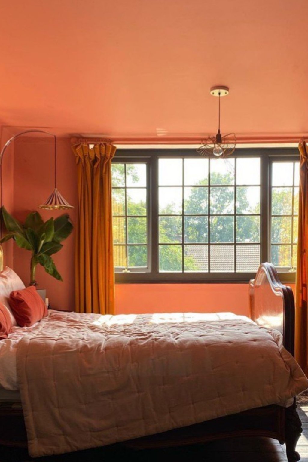 Warm orange-painted bedroom with yellow drapes and wooden furniture—classic warm tone orange color bedroom ideas.