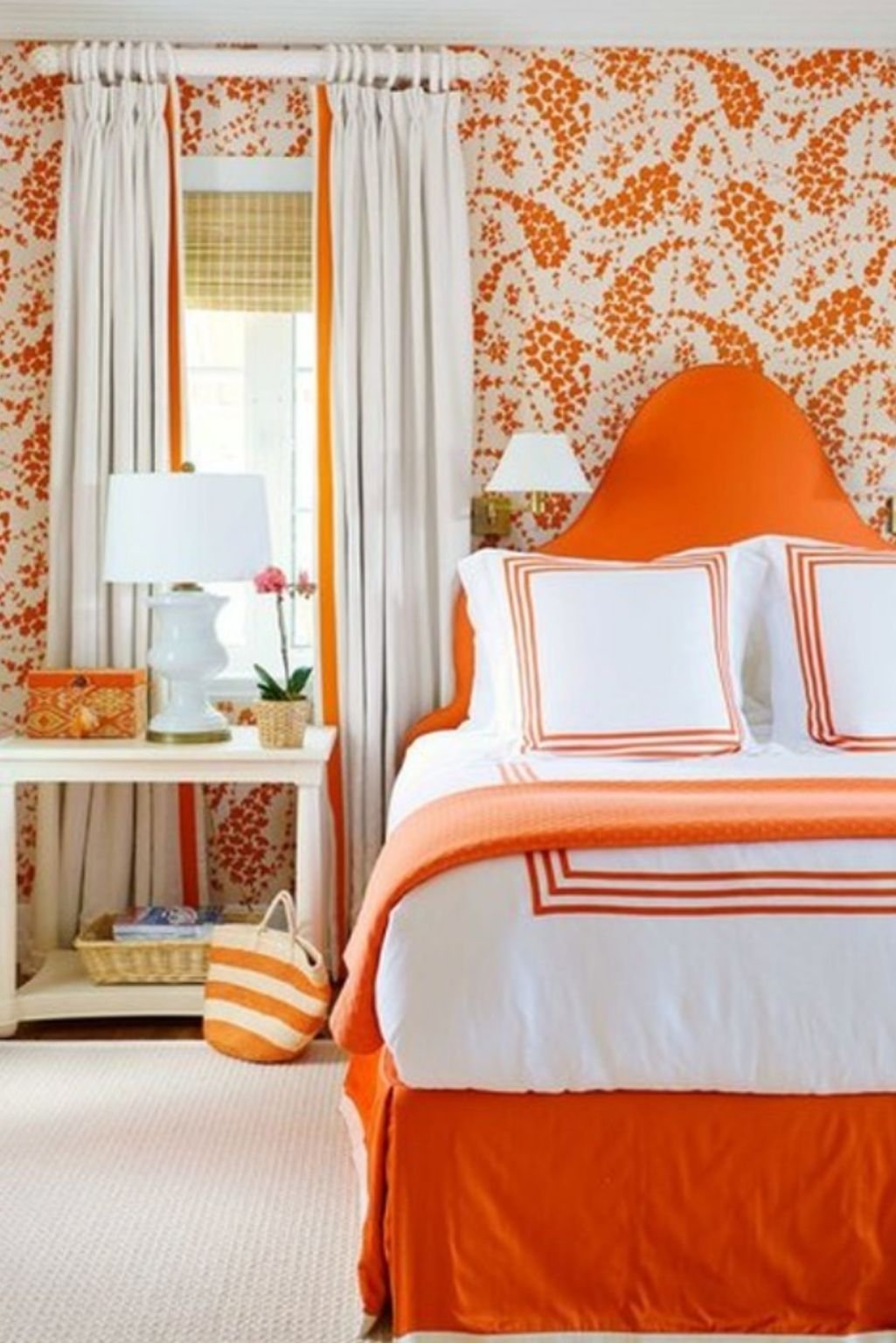 Orange-trimmed white bedding and floral wallpaper—playful and fresh orange color bedroom ideas.