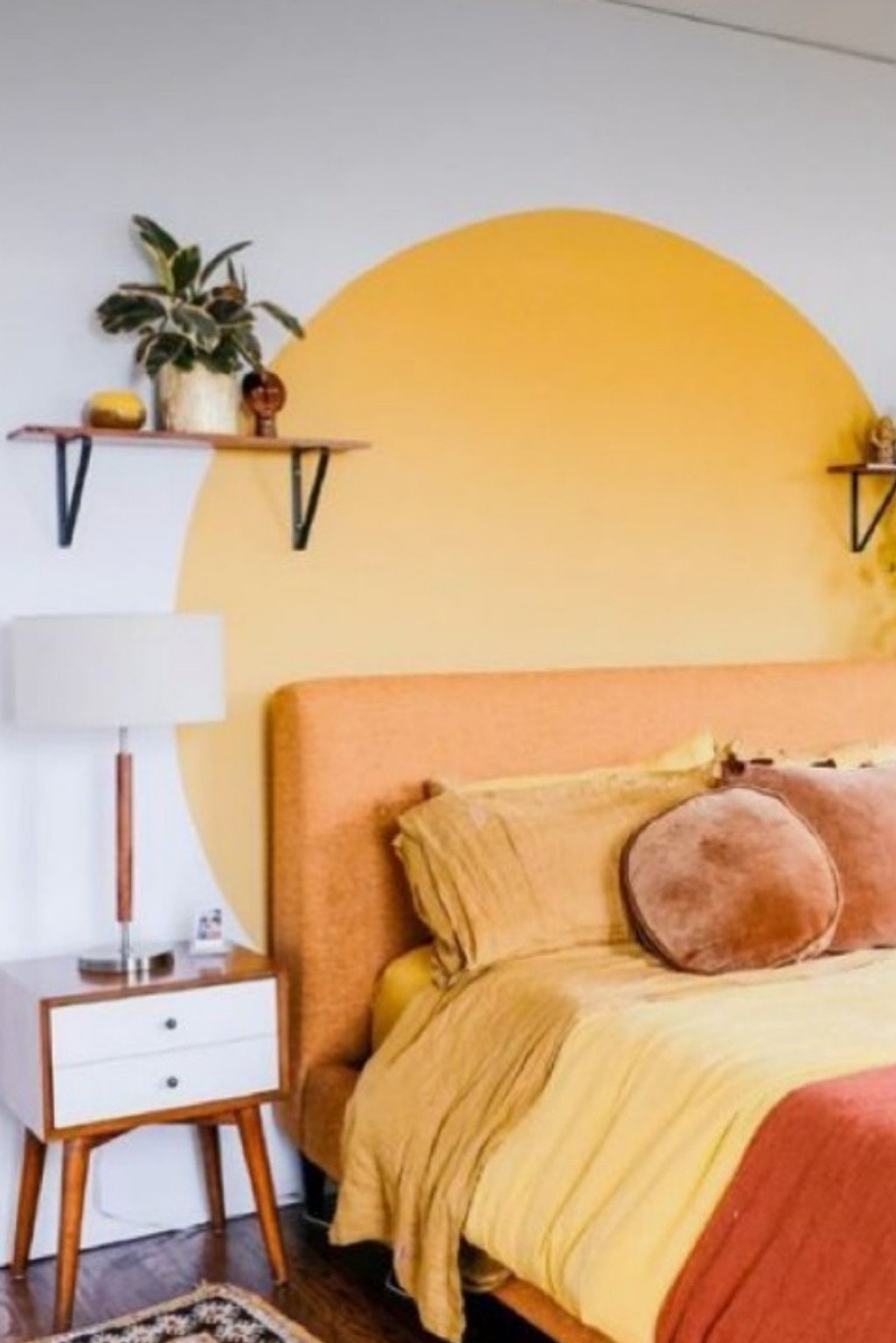 Yellow-orange arched wall, mustard bedding, and earthy tones—cozy and clever orange color bedroom ideas for small spaces.