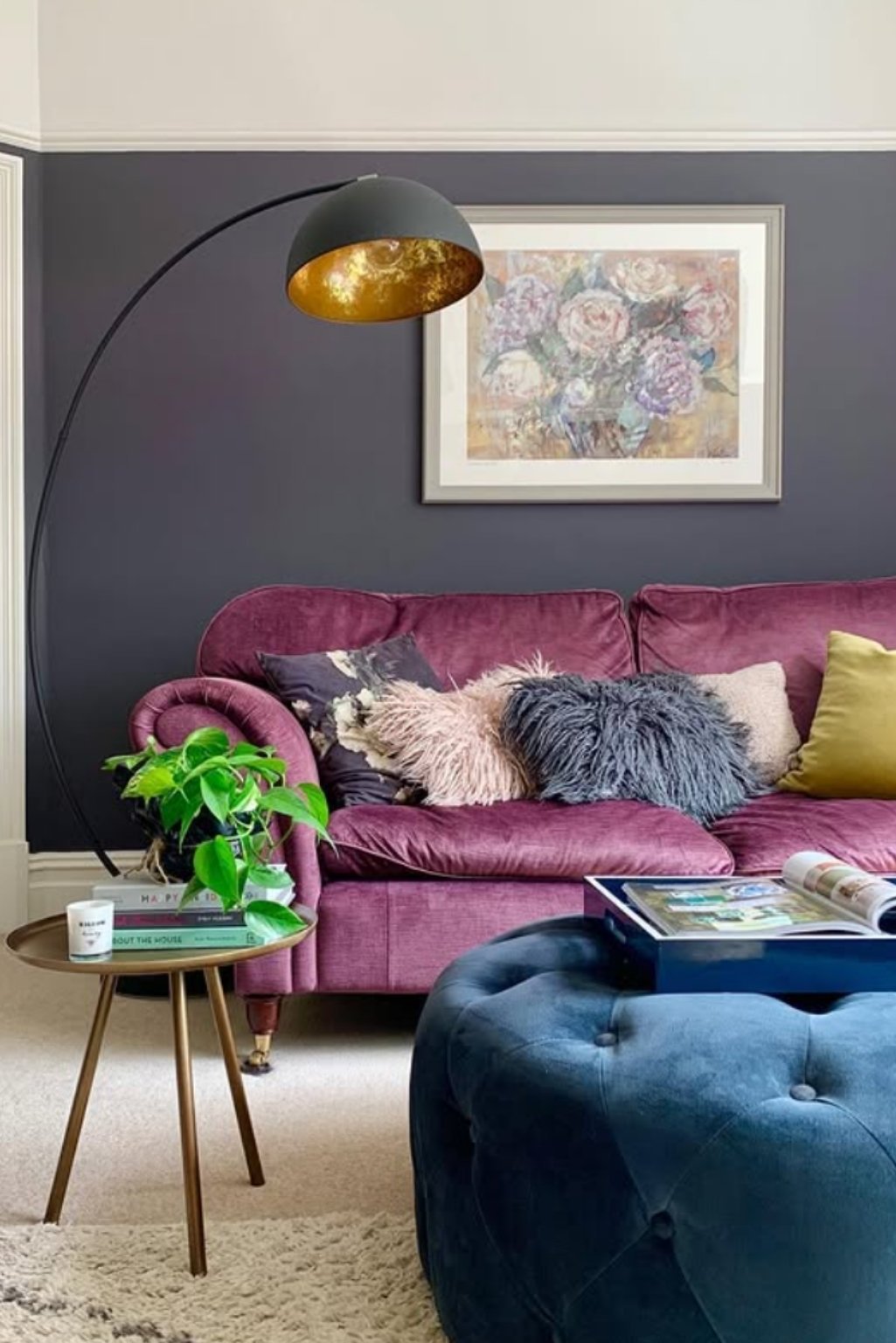 Raspberry-toned purple seating with fur pillow, soft rug, and stylish brass floor lamp.
