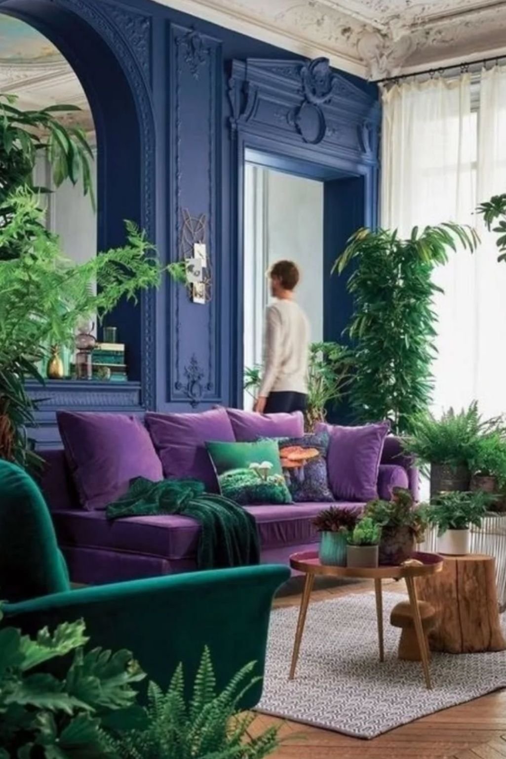 Vibrant purple sofa set against deep blue walls with plants and crown molding.