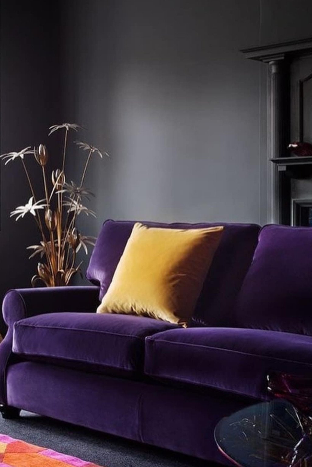 Deep purple velvet sofa with mustard pillows and dark gray walls