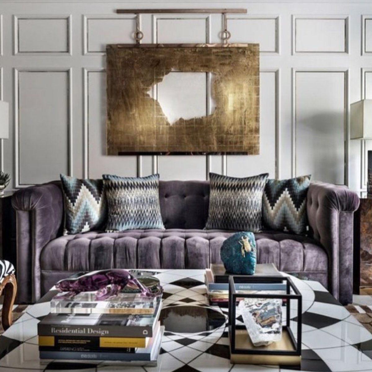 Tufted velvet purple sofa in a Parisian-inspired room with gold-framed mirror and white paneling.