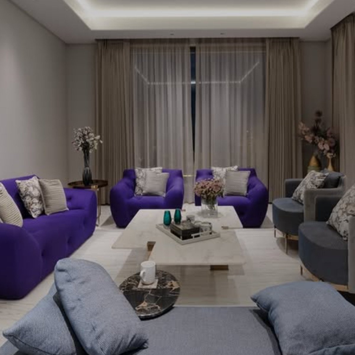 Two matching purple sofas in a formal symmetrical layout with light gray chairs.
