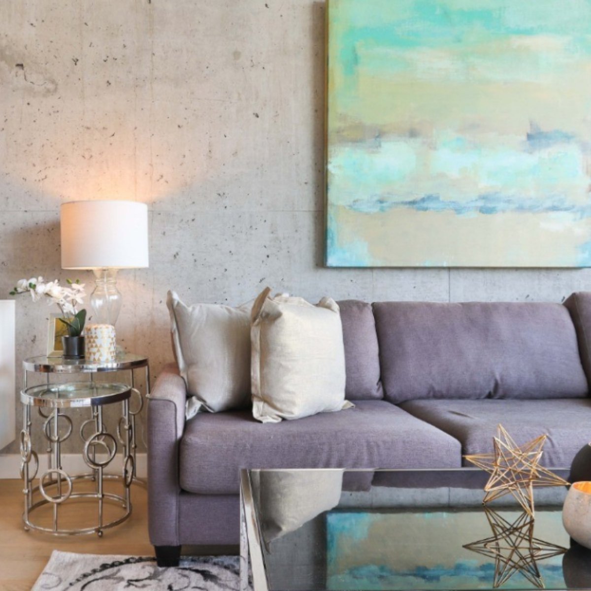 Light lavender sofa with neutral cushions and abstract wall art on a textured gray wall.