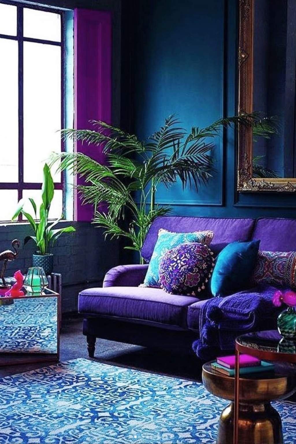 Deep purple sofa surrounded by jewel-toned blue walls, gold accents, and plants.