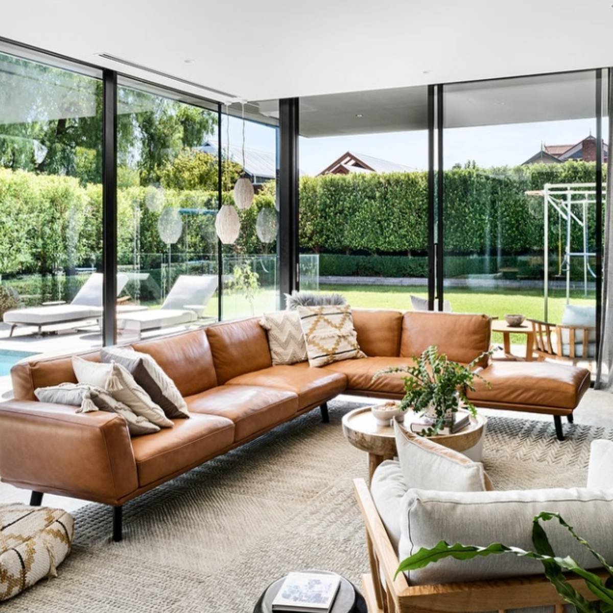 Bright open-plan living room with large tan sectional and garden views