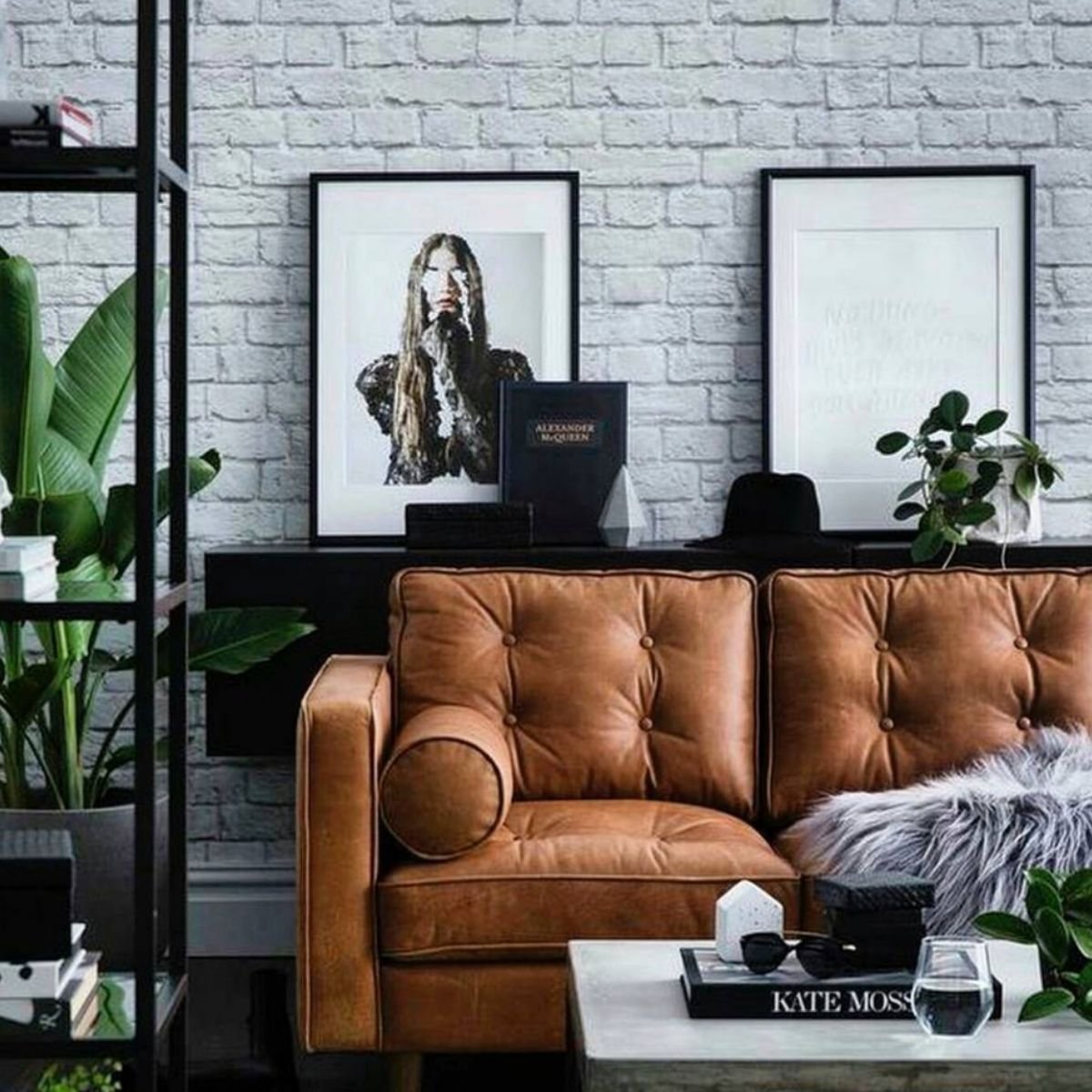Tan tufted sofa with whitewashed brick wall and monochrome artwork