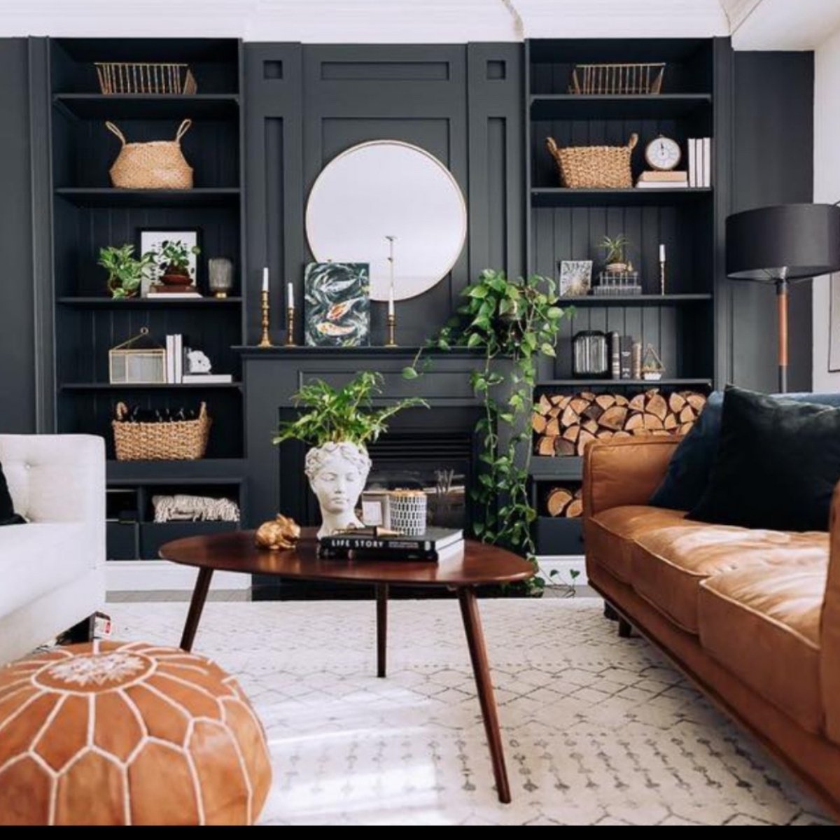 Dark-toned library living room with tan leather sofa and built-in bookshelves