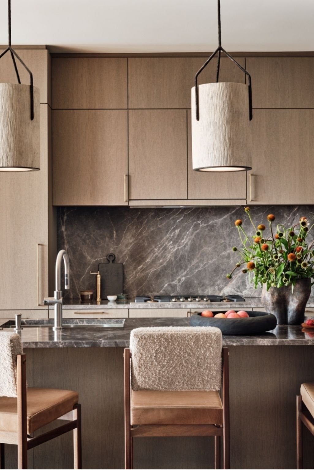 White oak kitchen cabinets paired with dramatic natural stone countertops and backsplash for a rich, earthy kitchen design.