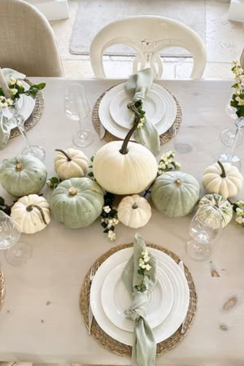 Sage green and white pumpkins used as part of a muted-toned fall table arrangement.